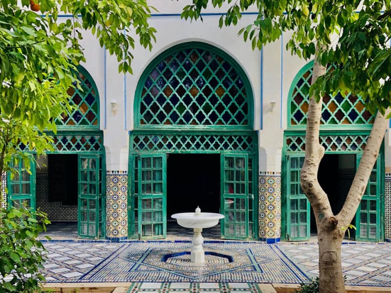 # Alt Text Moroccan riad courtyard with turquoise doors, fountain and zellige tilework