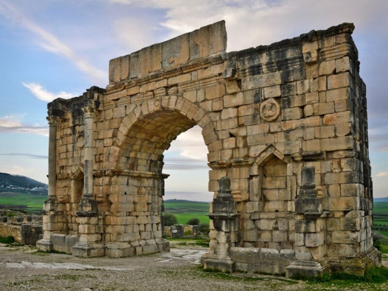 # Alt Text Volubilis Roman arch ruins Morocco ancient stone gateway landscape