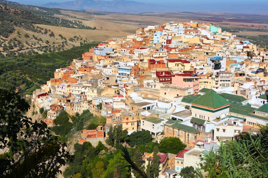 Moulay Idriss Zerhoun, Morocco, with a hillside medina of tightly packed white and beige buildings overlooking open countryside.